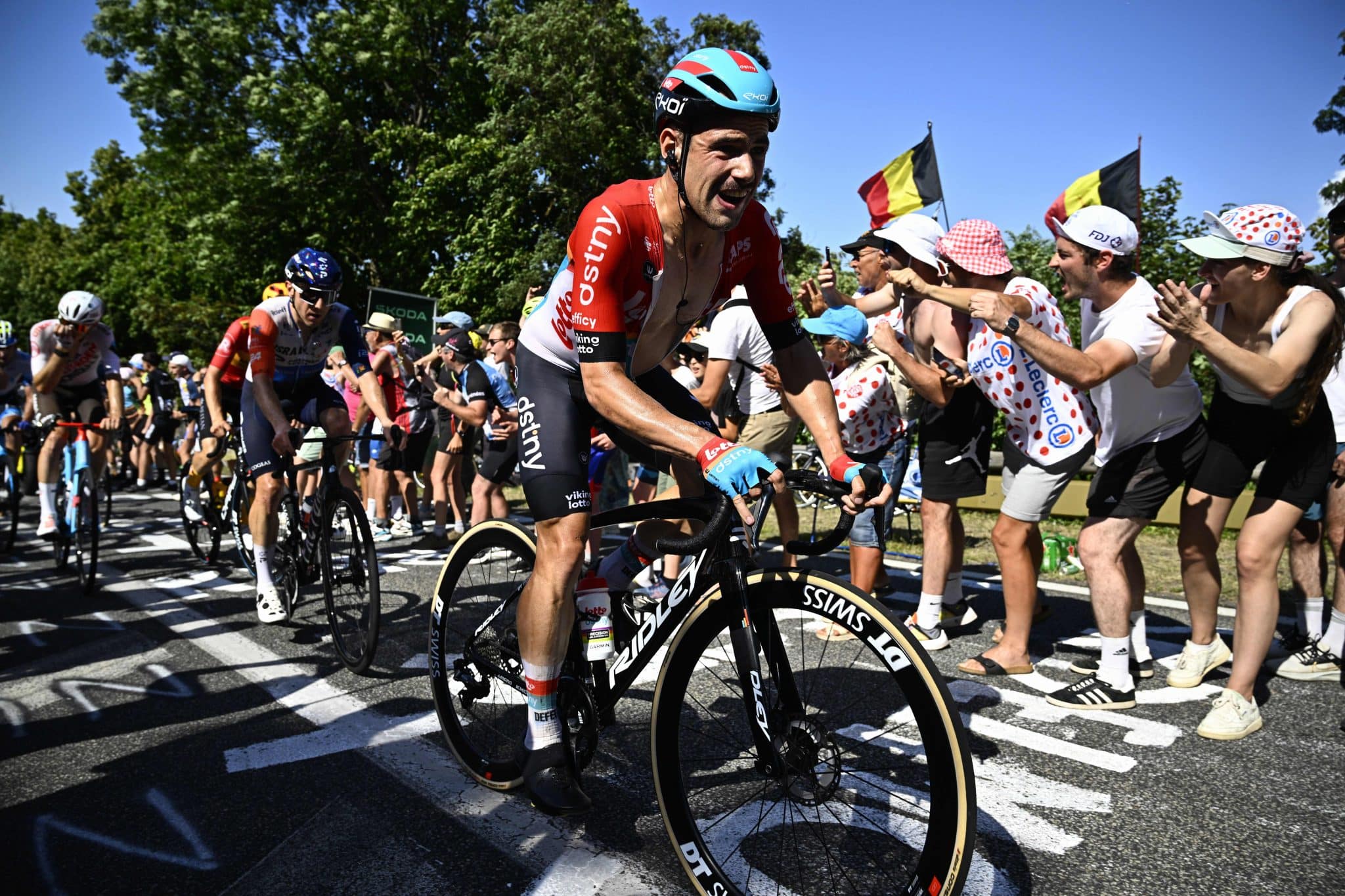 two professional cyclists on their bikes with spectators in the background